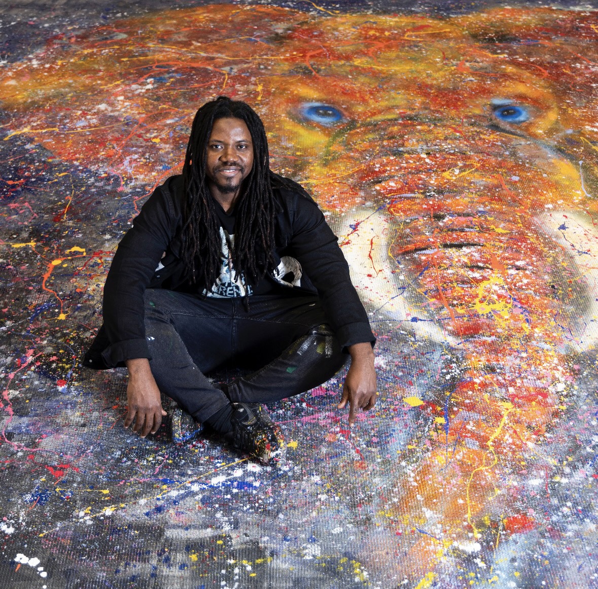 Bruce Karim seated on his large elephant painting, Sound of Freedom.