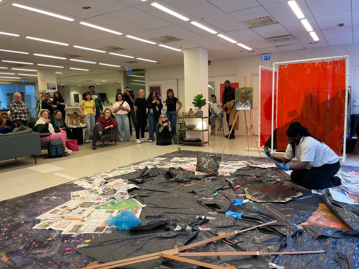 An audience gathered around Bruce Karim's floor-based RISE UP performance at Amnesty Artivism in 2026.