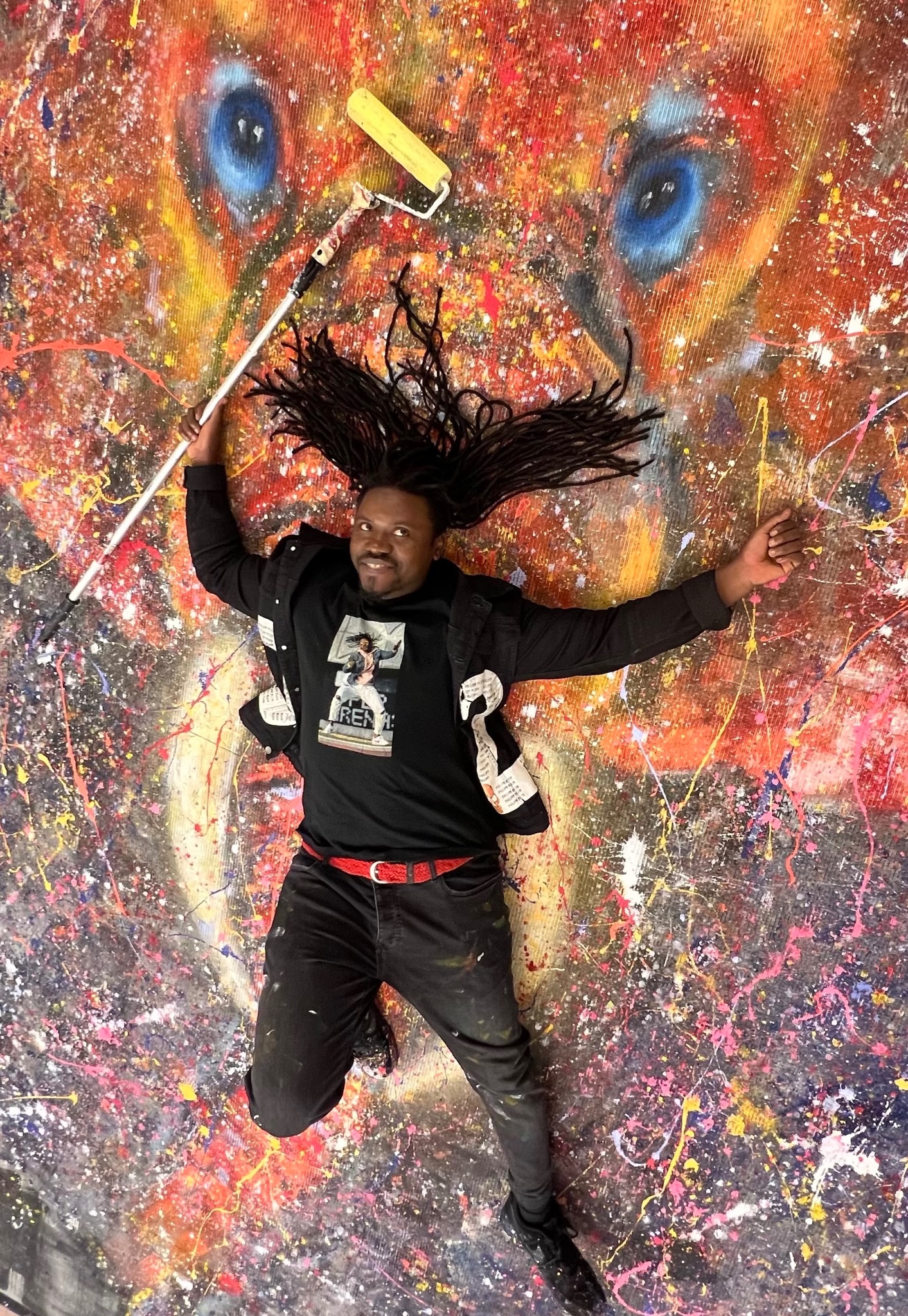 Bruce Karim lying on Sound of Freedom with his hair spread across the painted surface, holding a paint roller.