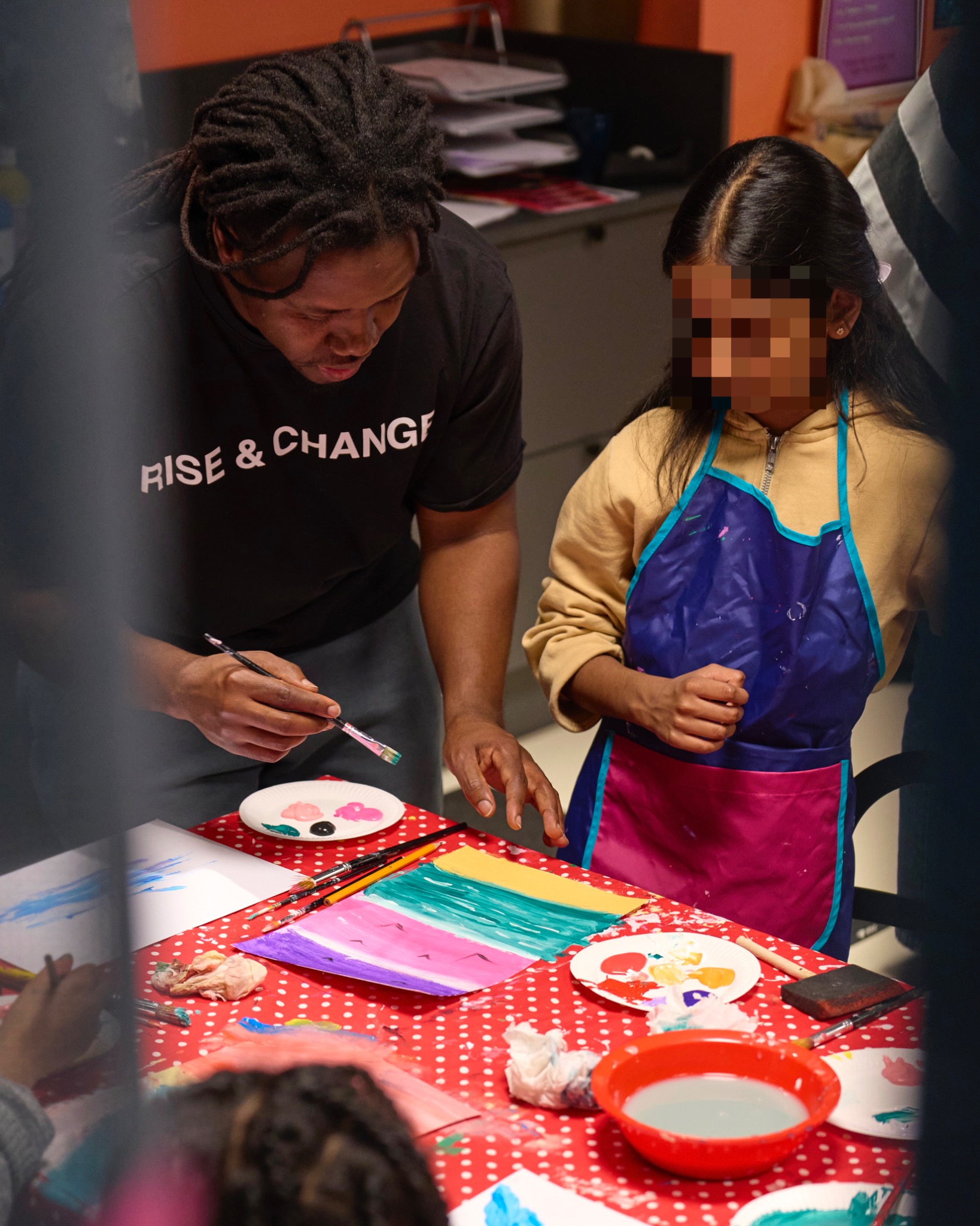 Bruce Karim guiding a young participant during a Rise & Change art workshop.