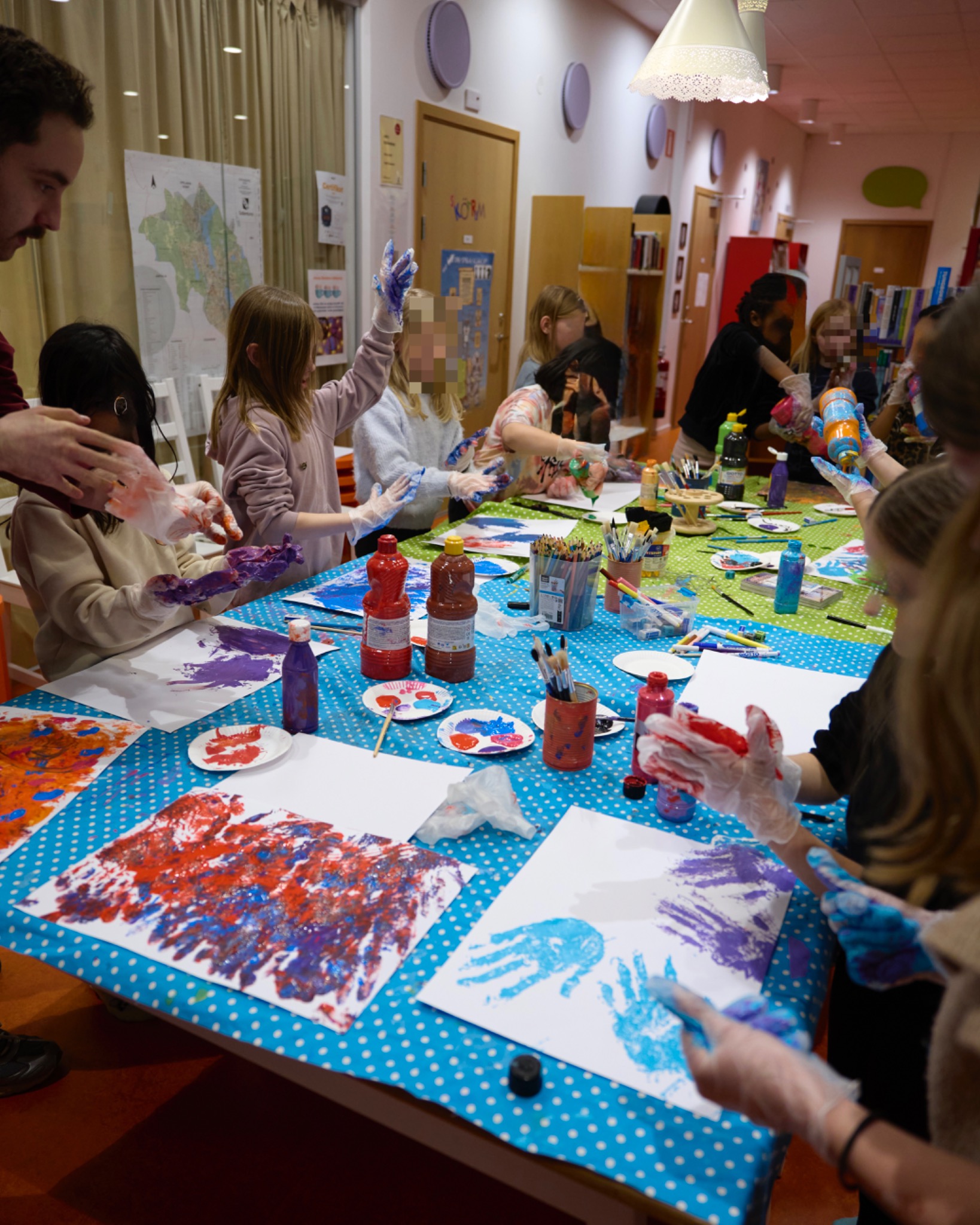 Participants and leaders exploring paint together around a shared workshop table.