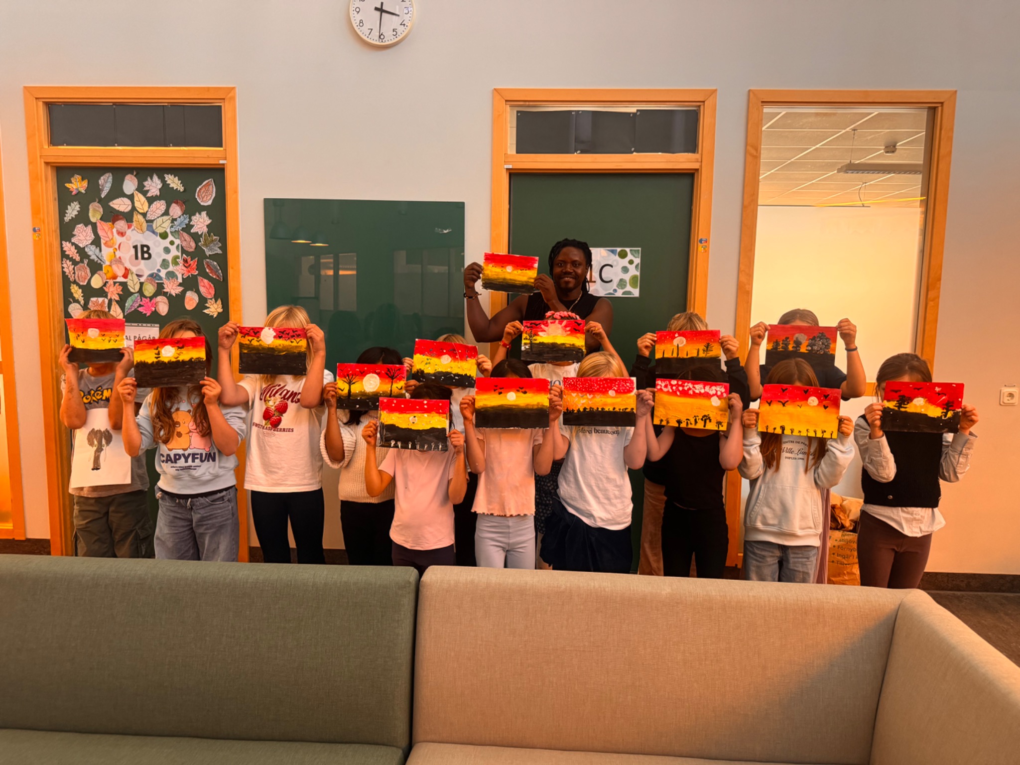 Bruce and a group of children holding up their sunset paintings after a creative workshop.