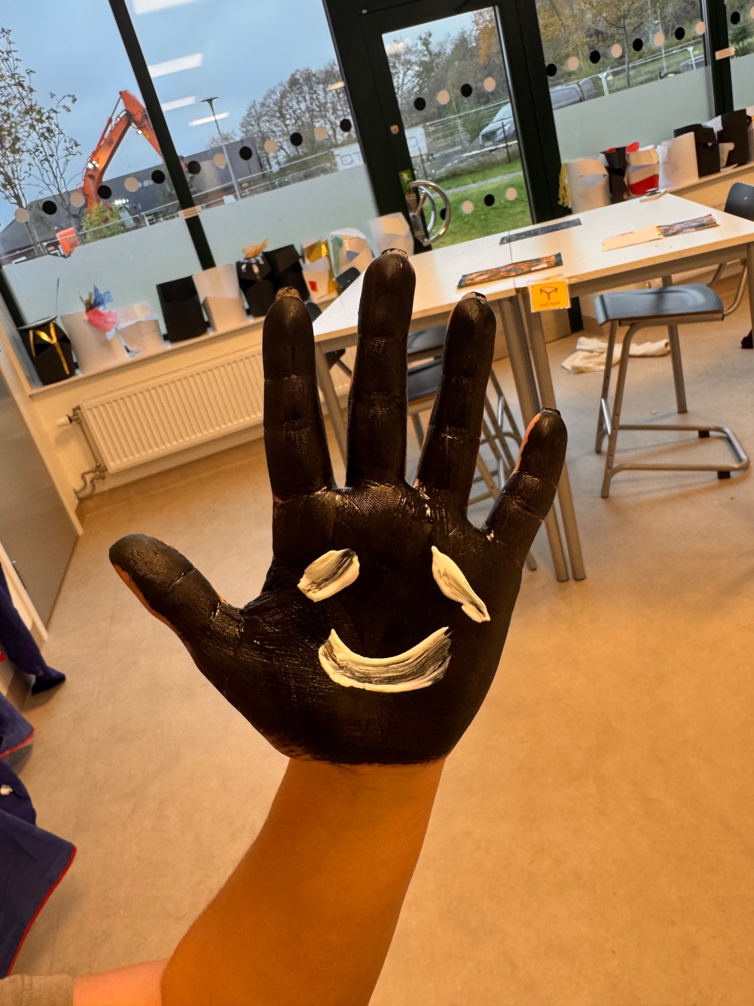 A black-painted open hand with a white smile.